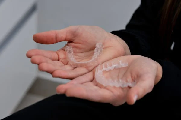 A person holding a set of transparent teeth cover in is hands