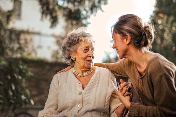 an old  woman suffering in Dementia  and smiling a young woman 