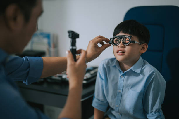 Asian chinese boy with phoropter having testing his eyes in the doctor's office